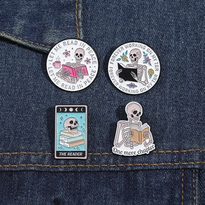 Detailed close-up of colorful enamel skeleton book pins on dark blue denim fabric background