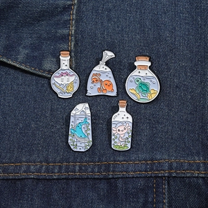 Detailed close-up of colorful ocean life enamel pins set on dark blue denim fabric background