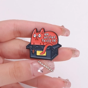 Detail of cartoon cat enamel pin with 'NO DESIRE TO FIT IN' text on black box