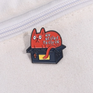 Close-up of red cat enamel pin on canvas with text No Desire To Fit In
