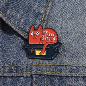 Funny orange cat in blue box enamel pin on denim jacket with 'No Desire to Fit In' slogan
