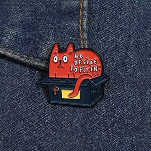 Detail of red cat enamel pin in a box on denim jacket with NO DESIRE TO FIT IN text
