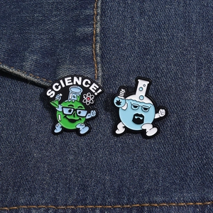 Detail view of Science themed enamel pins on denim fabric with beaker and chemist motifs