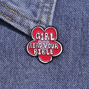 Macro shot of a red flower enamel pin with Girl Read Your Bible text on denim fabric