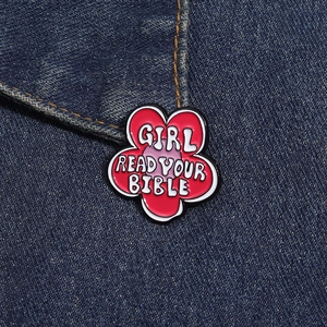Detail of pink flower enamel brooch with GIRL READ YOUR BIBLE text on denim fabric