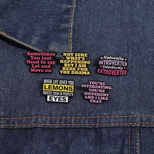 Set of five creative black enamel pins with colorful quotes on denim jacket