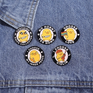 Detailed close-up of five creative yellow duck enamel pins on dark blue denim fabric texture