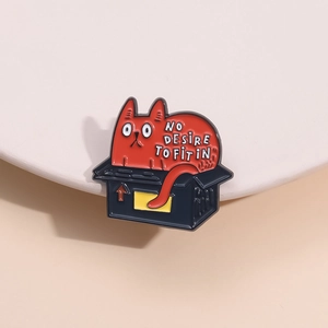 Cartoon enamel pin of a red cat in a black box with No Desire To Fit In slogan