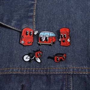Detailed view of red cartoon enamel pins including bus and phone booth on blue denim