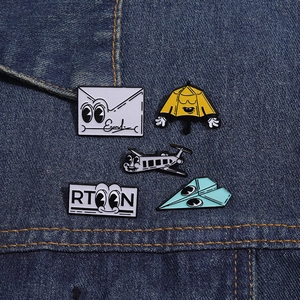 Lot de 5 pin's en émail avion en papier et enveloppe sur une veste en jean bleue