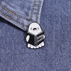 Close-up of a ghost reading Human Stories enamel pin on blue denim fabric texture
