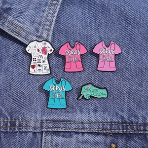 Close-up of 5-piece medical enamel pins featuring colorful scrubs and scalpel on denim
