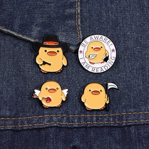 Vue détaillée de quatre pins en émail de canards jaunes sur tissu denim bleu foncé