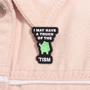 Detail of funny green frog enamel pin with I MAY HAVE A TOUCH OF THE TISM text