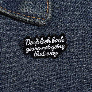 Détail du pin's en émail avec citation inspirante sur fond en tissu denim