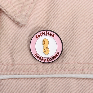 Dettaglio ravvicinato della spilla smaltata rosa Goofy Goober su tessuto denim