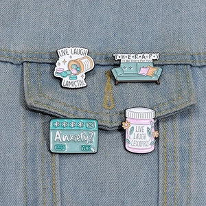 Detailed view of mental health enamel pins on denim jacket featuring medicine bottle designs
