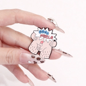 Handheld enamel pin featuring 'GOOD FEELS' text and creative cartoon body shape design