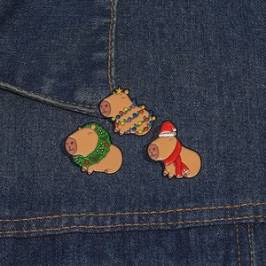 Detailed macro shot of festive Capybara enamel pins with Christmas hats and wreaths