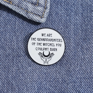 Detail of feminist enamel pin with moon graphic on blue denim jacket fabric