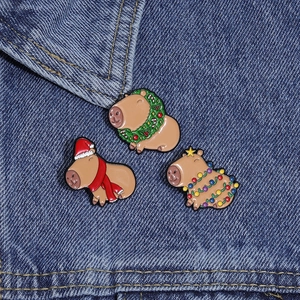 Three cute Christmas capybara enamel pins on denim, featuring festive hats and light strings