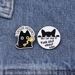 Detail of funny black cat enamel pins with witty text on blue denim fabric background