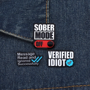 Close-up of funny enamel pins with social media quotes on denim fabric background