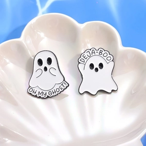 Close-up of enamel ghost brooches with Oh My Ghost and Deja-Boo slogans on a shell tray