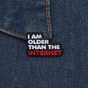 Macro shot of I AM OLDER THAN THE INTERNET enamel pin badge on blue denim jacket