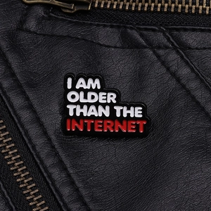 Close-up of I AM OLDER THAN THE INTERNET enamel pin on a black leather jacket