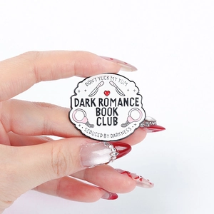 Dark Romance Book Club Emaille-Pin mit Handschellen und Dolch in der Hand gehalten