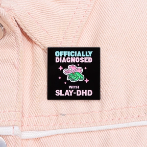 Detail of pink cowboy frog enamel pin with Slay-DHD slogan on pink denim fabric
