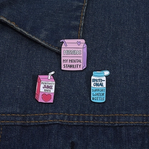 Close-up of three creative cartoon enamel pins featuring mental health slogans on denim
