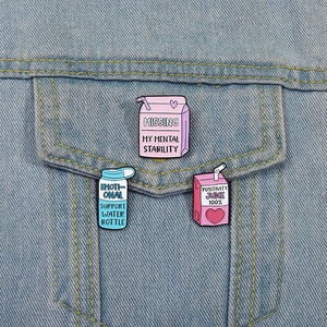Three-piece cartoon enamel pins set featuring a milk box and juice bottle on denim