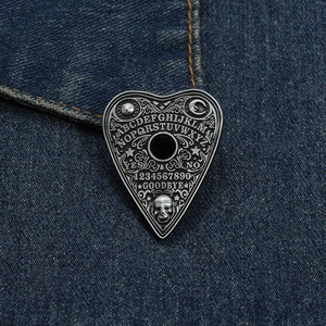 Macro view of gothic heart brooch with Ouija board engraving on blue denim fabric