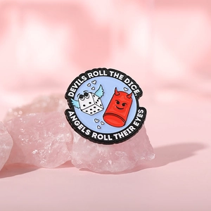 Macro shot of circular enamel brooch with devil and angel dice on pink crystals