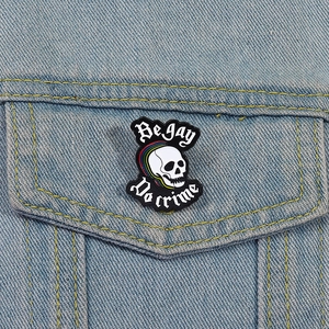Détail du pin's émaillé crâne arc-en-ciel avec texte sur une veste en jean bleue
