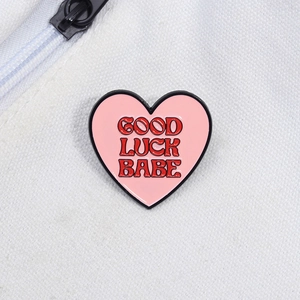 Gros plan détaillé du pin's en émail en forme de cœur avec texte Good Luck Babe