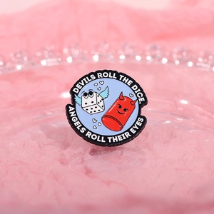 Close-up of enamel pin with white dice, red devil and Taylor Swift lyrics on glass