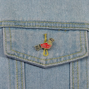 Détail du pin's émaillé main rose rouge avec texte Bad Seed sur veste en jean