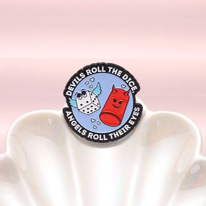 Detail of round enamel pin with devil, winged dice and pearl shell background texture