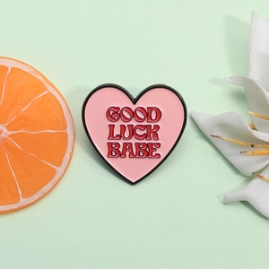 Broche cœur rose en émail avec texte Good Luck Babe sur un fond vert rafraîchissant