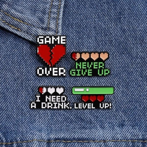 Detail of pixel art game style enamel pins set with heart health bars on denim fabric