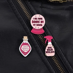 Detail of three pink enamel pins with bookworm slogans on a black leather jacket