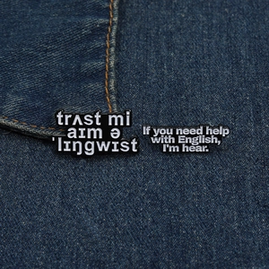 Close-up of enamel pins with linguistic humor pinned on blue denim fabric background