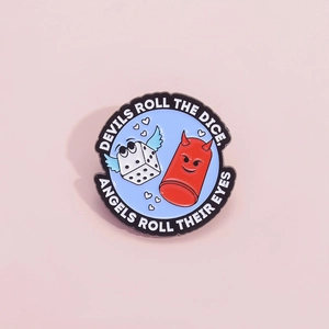 Blue enamel pin with winged dice design and Devils Roll the Dice printed slogan