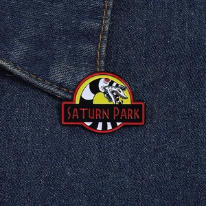 Detailed view of the Saturn Park enamel pin featuring a snake logo on denim jacket