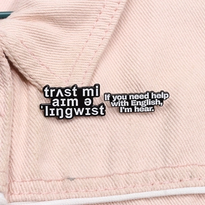 Close-up of enamel letter brooches with humorous English text on a pink denim collar