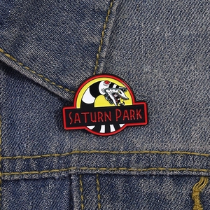 Enamel brooch with black and white snake design and Saturn Park logo on denim jacket
