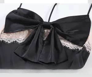 Détail du caraco en satin noir avec grand nœud et bordure en dentelle de cils